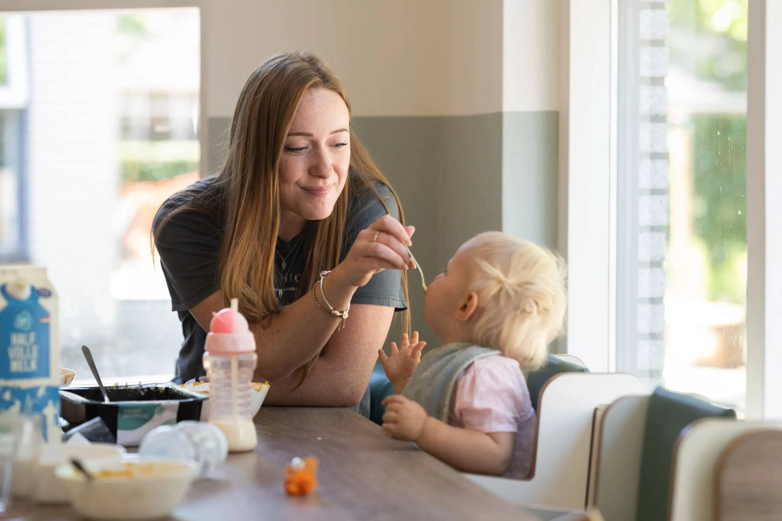 Kinderdagverblijf medewerker geeft eten aan kind