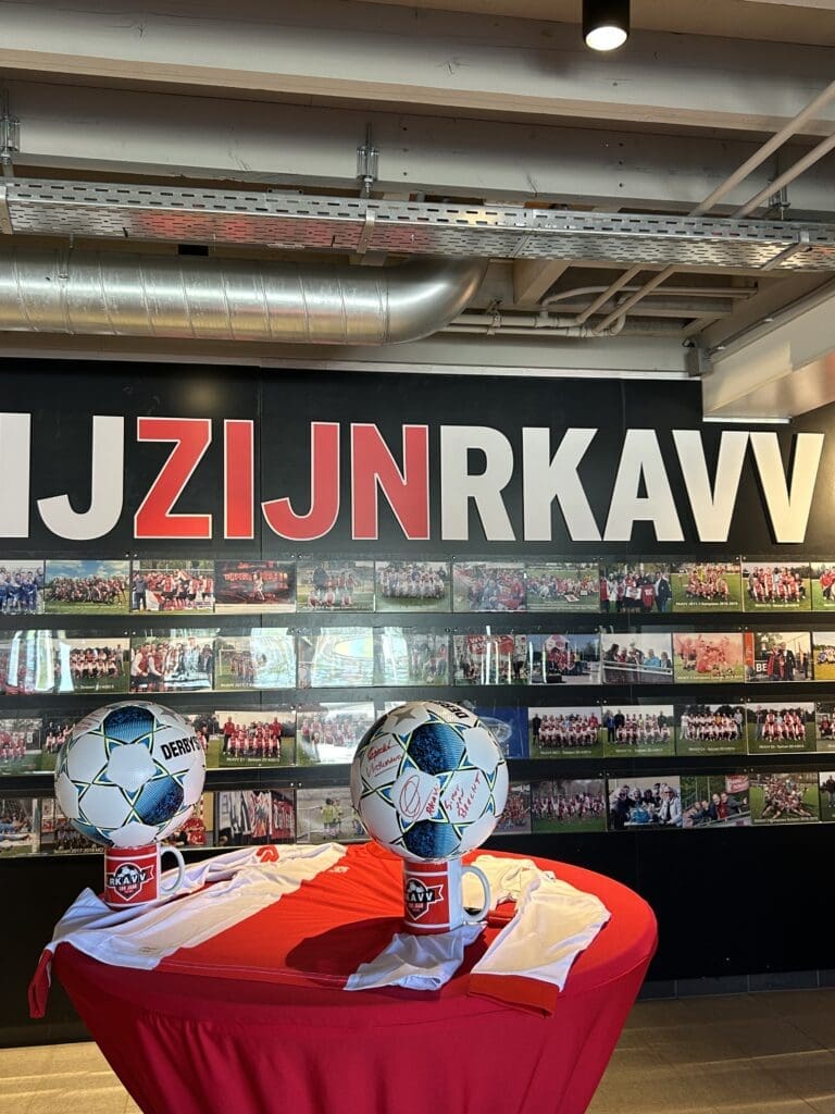 Vlietkinderen en RKAVV - Twee voetballen gebalanceerd op mokken met twee shirts