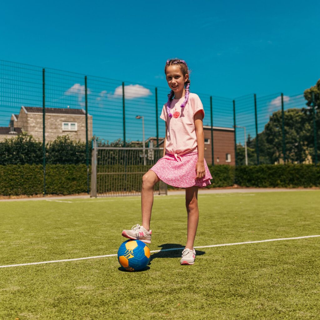 Kind speelt voetbal tijdens een buitenschoolse opvangactiviteit van Vlietkinderen in Voorburg.